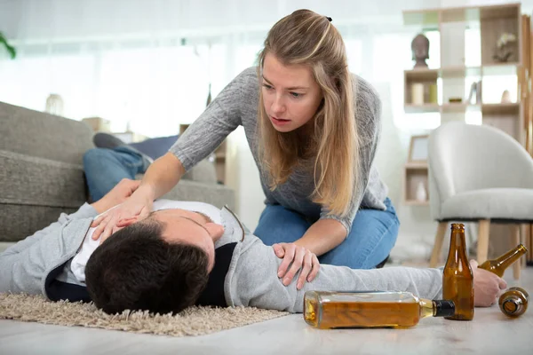 Γυναίκα Ανησυχεί Για Τον Μεθυσμένο Σύζυγο Ξαπλωμένο Στο Πάτωμα — Φωτογραφία Αρχείου