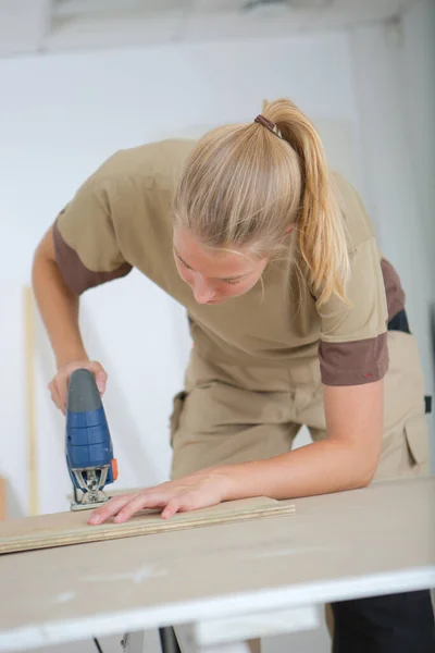 自宅で死ぬ女性が作業台で木の板を切断し — ストック写真