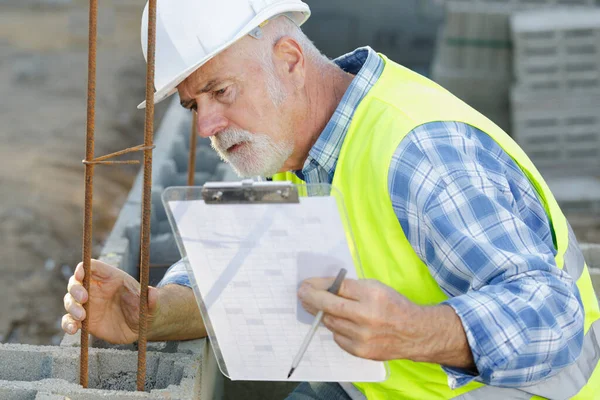 man builder in hardhats with clipboard at construction site