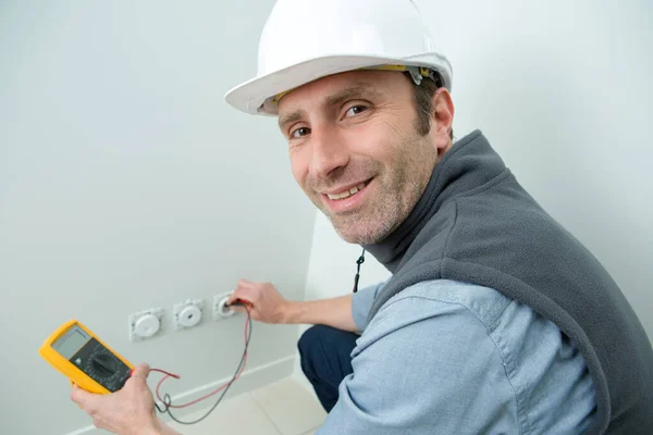 电工们愉快地检查电壁插座上的电压 — 图库照片