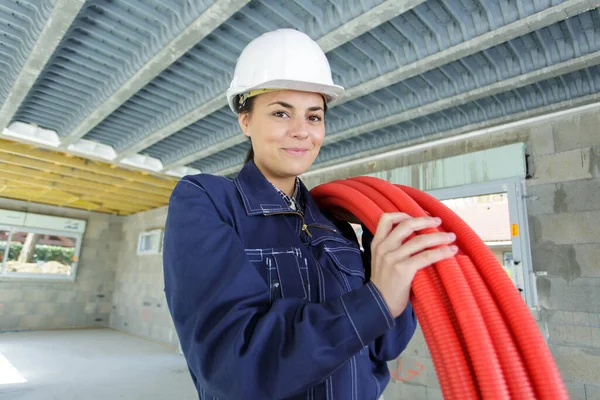 女建筑工人肩上扛着红管卷轴 — 图库照片