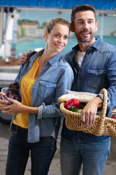 在市场上散步的夫妇提着一个装有蔬菜的篮子 — 图库照片