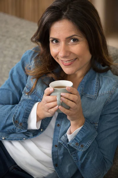 ソファでお茶を飲みながらリラックスする女性 — ストック写真