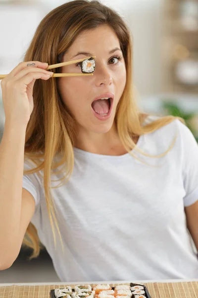 年轻女子的眼睛上握着一块寿司 — 图库照片