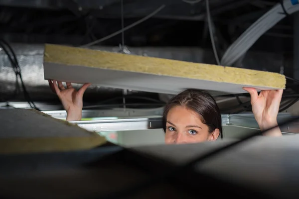 stock image Woman lowering insulated board back into ceiling