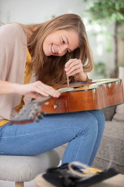 修理吉他的年轻快乐的女人 — 图库照片