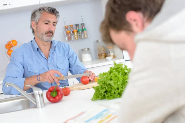 Man Preparing Vegetables While Boy Reads Book — Stock Photo, Image