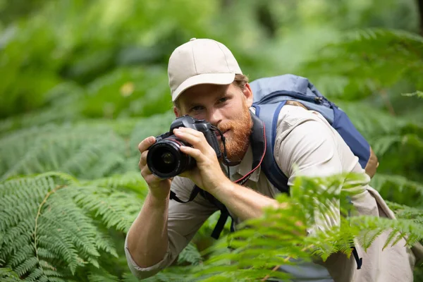 男人拿着相机在森林里拍照 — 图库照片