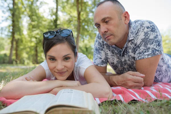 公園で女と本を見ている男は — ストック写真