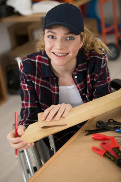 使用圆锯坐在轮椅上的快乐的年轻女子 — 图库照片