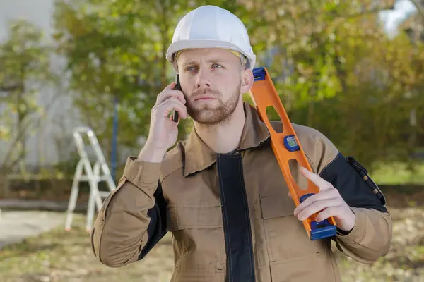 Trabajador Construcción Sosteniendo Nivel Espíritu Tusing Teléfono Celular — Foto de Stock