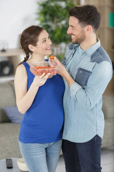 厨房里有西红柿的怀孕夫妇 — 图库照片