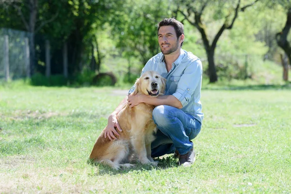 一个带着狗在草地上笑的男人 — 图库照片