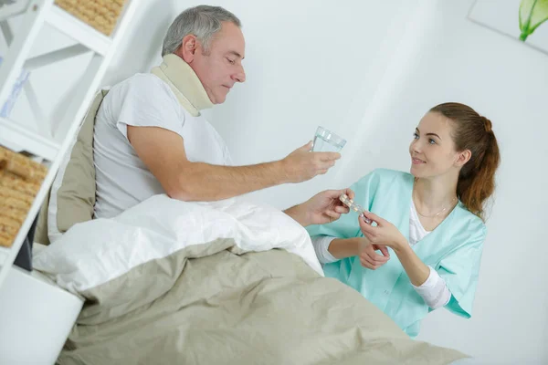 Verzorger Geeft Medicatie Aan Middelbare Leeftijd Man Bed — Stockfoto