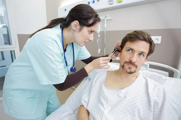 女性医師が患者の耳を調べ — ストック写真