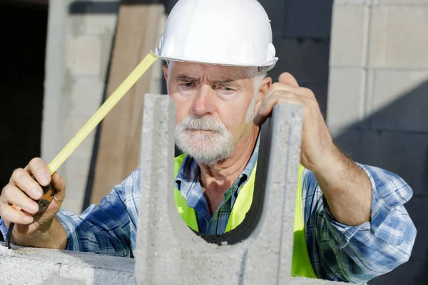 Pracownik Budowlany Stosujący Miernik Taśmowy Ścianie Bloku Betonowego — Zdjęcie stockowe
