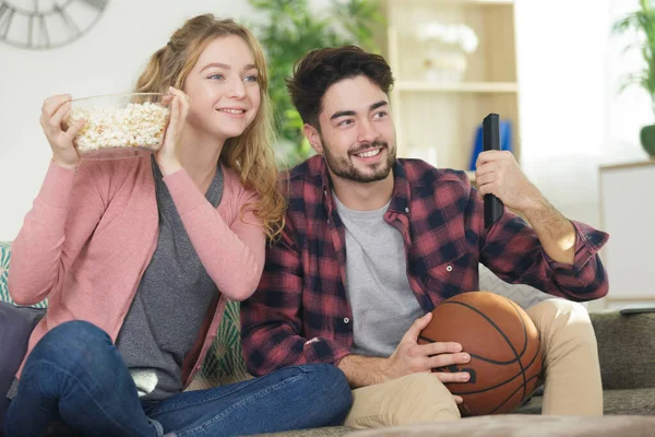 若いカップルがテレビでバスケットボールを見て — ストック写真