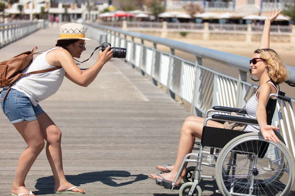 给坐在轮椅上的女友拍照的女人 — 图库照片