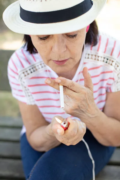 Mujer Mayor Banco Sosteniendo Cigarrillo Fumando —  Fotos de Stock