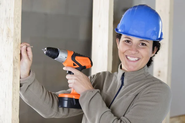 新しい家の中で幸せな女性の掘削壁 — ストック写真