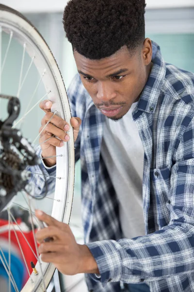 handsome bike mechanic repairs bicycle in workshop