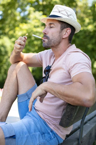 Mann Raucht Zigarette Und Entspannt Sich Auf Bank — Stockfoto