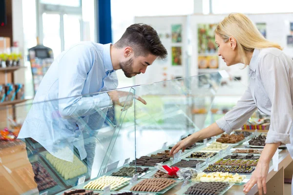 若い男が店内でチョコレートを選ぶ — ストック写真