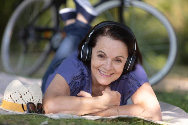 Yetişkin Bir Kadın Çimlerin Üzerinde Yatarken Müzik Dinliyor — Stok fotoğraf