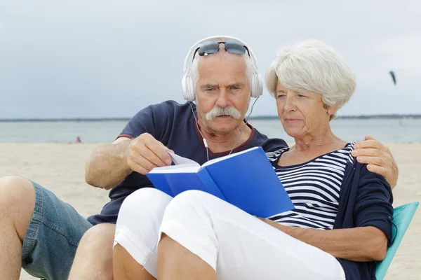 老夫妇在海滩上看书 — 图库照片