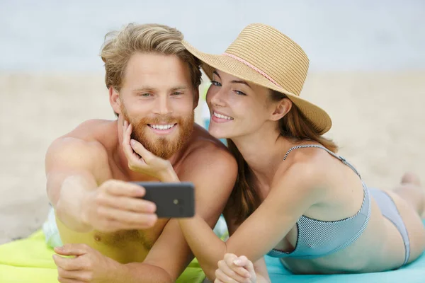 ビーチでスマートフォンを手にしたカップルは — ストック写真