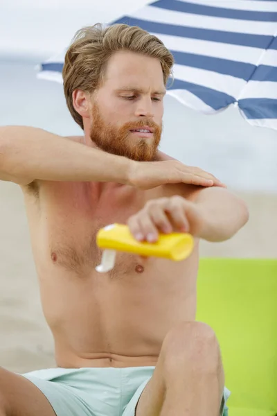 男人在海滨度假时放奶油 — 图库照片