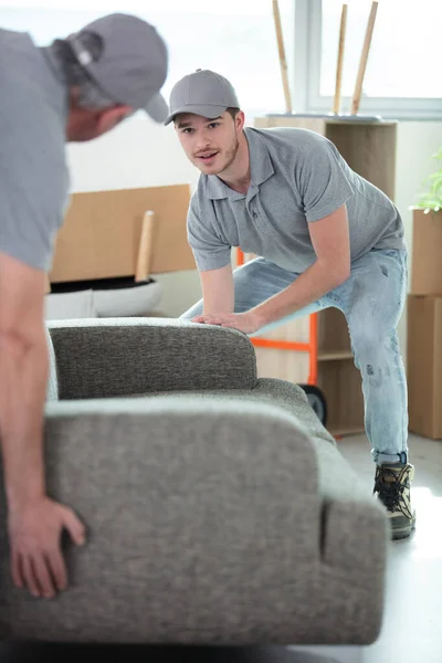 Male Movers Placing Sofa Hardwood Floor Home — Stock Photo, Image