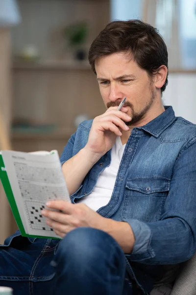 Young Man Sitting Doing Crossword Puzzle — Stock Photo, Image