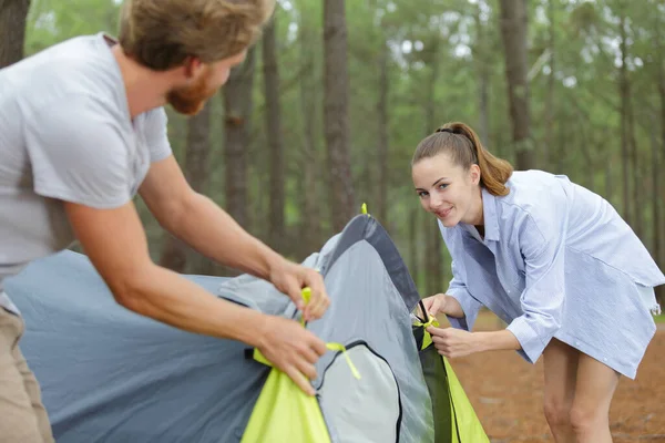 森でキャンプ中のテントを作るカップル — ストック写真