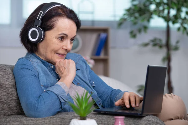 Ανώτερος Γυναίκα Στο Σπίτι Για Φορητό Υπολογιστή Ακουστικά — Φωτογραφία Αρχείου
