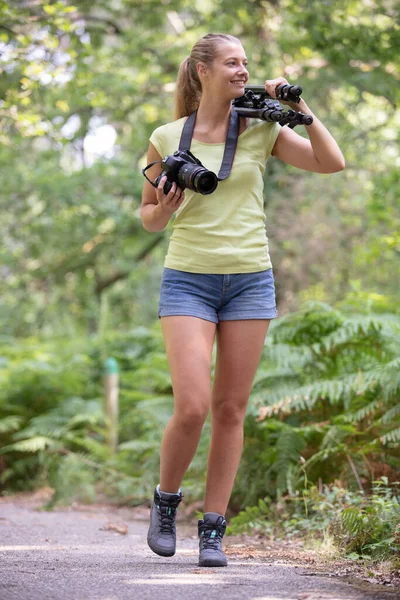 女摄影师带着三脚架在农村行走 — 图库照片