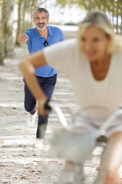 Senior Man Playfully Chasing Woman Bicycle — Stock Photo, Image