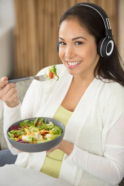 Χαρούμενη Γυναίκα Που Φοράει Ακουστικά Ενώ Τρώει Γεύμα Της Σαλάτας — Φωτογραφία Αρχείου