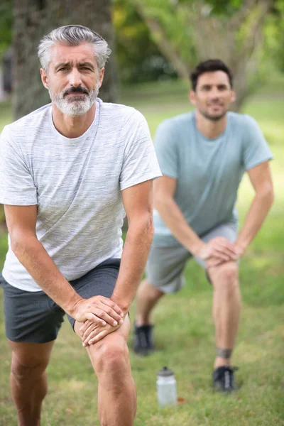 Dwóch Mężczyzn Ćwiczących Rozprostowanie Nóg — Zdjęcie stockowe