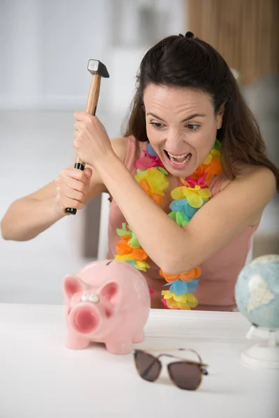 woman is smashing piggy bank with hammer