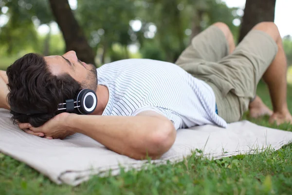 Šťastný Muž Poslouchá Hudbu Zatímco Leží Trávě — Stock fotografie