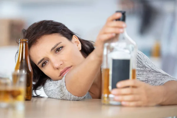 Drunk Woman Slumped Table Holding Bottle Alcohol — Stock Photo, Image