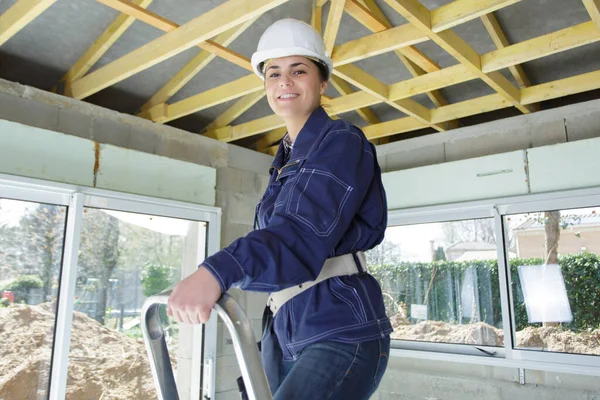 年轻的女建筑工人站在梯子上 — 图库照片