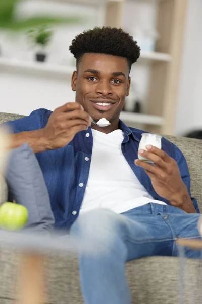 Ung Man Äter Yoghurt Soffan — Stockfoto
