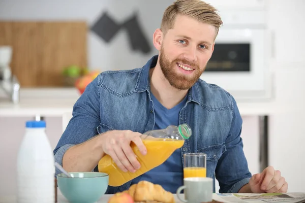 オレンジジュースを注ぐ幸せな若い男 — ストック写真