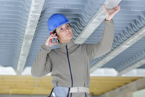女承建商检查混凝土屋面支撑物及使用智能手机 — 图库照片