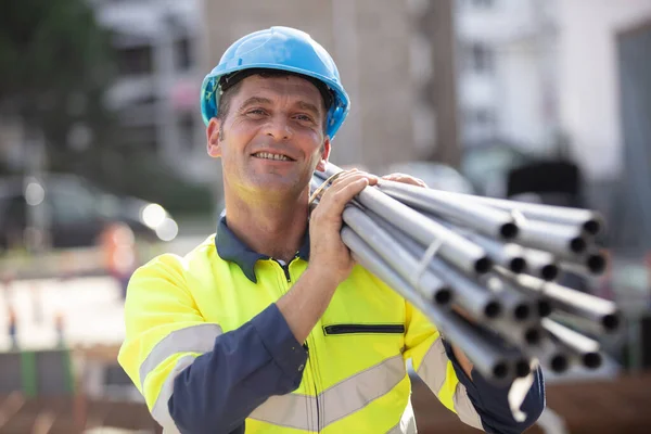 Arbeiter Trägt Auf Baustelle Rohre Auf Der Schulter — Stockfoto