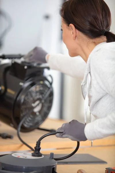 a woman looks at the electrical device