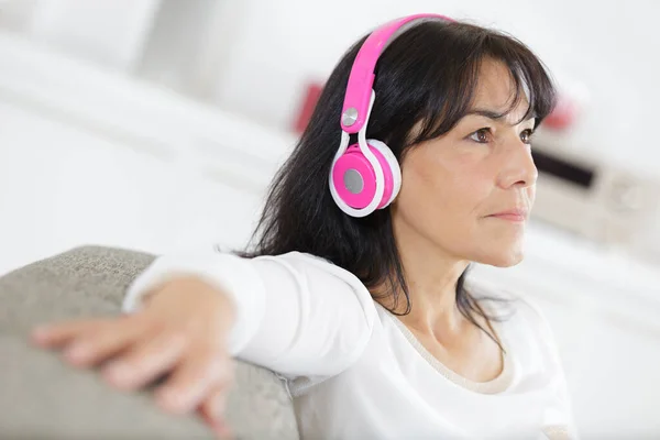 家でヘッドフォンで音楽を聴いている女性は — ストック写真