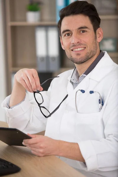 Mężczyzna Lekarz Siedział Przy Jego Biurku Trzymając Tablet — Zdjęcie stockowe